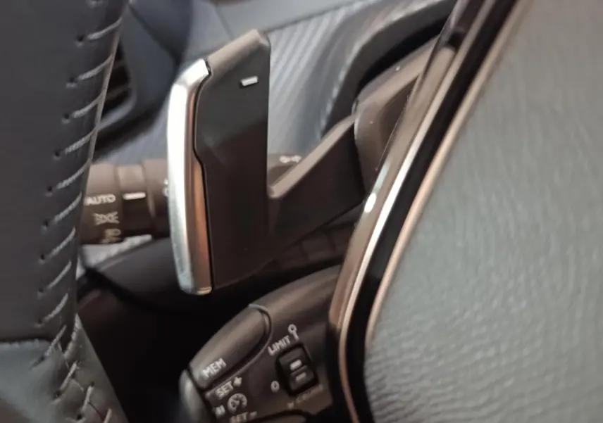 Gros plan sur la commande au volant cuir de la Peugeot 208 Hybrid 100 e-DCS6 Style gris clair, avec boutons multifonctions.