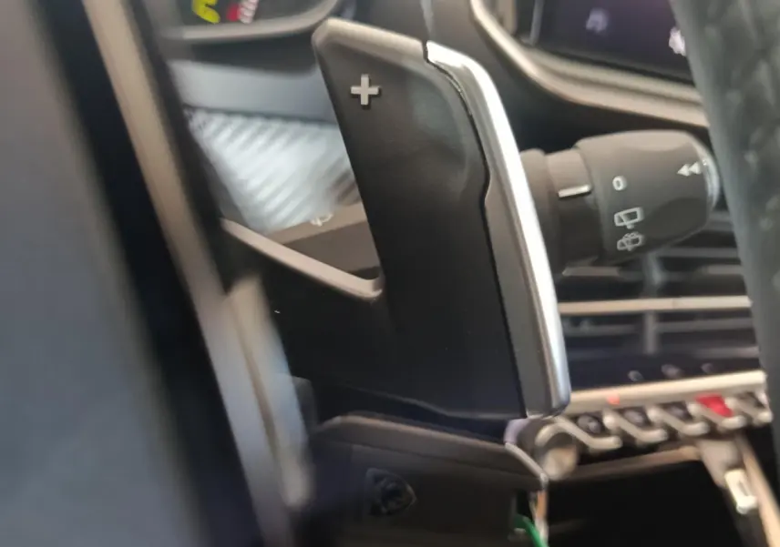 Gros plan sur la palette de changement de vitesse côté droit du volant dans l’habitacle d’une Peugeot 208 gris clair.