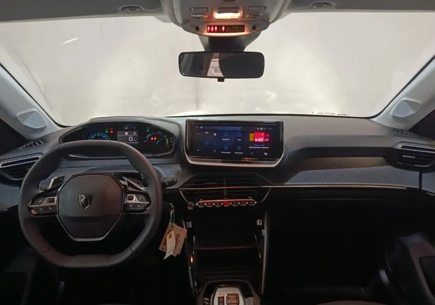 Vue intérieure avant du tableau de bord gris clair de la Peugeot 208 Hybrid avec écran tactile et volant multifonctions cuir.