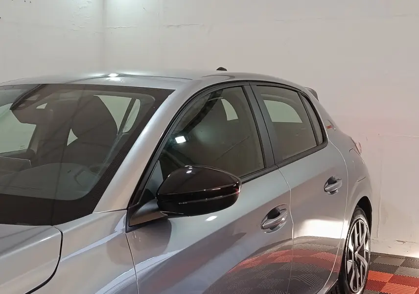 Vue latérale droite d'une Peugeot 208 Hybrid 100 e-DCS6 Style gris clair avec rétroviseur noir brillant.