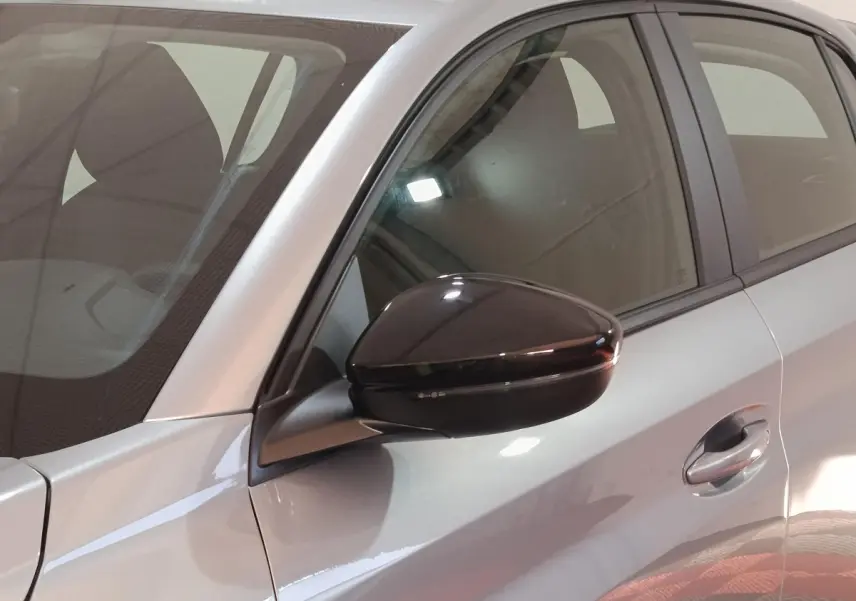 Gros plan sur le rétroviseur noir et la portière côté conducteur d’une Peugeot 208 Hybrid gris clair.