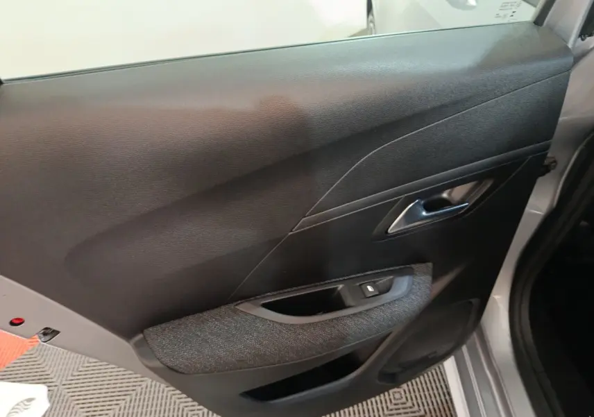 Vue rapprochée de la porte arrière droite gris clair du Peugeot 208 Hybrid 2025 avec habillage noir et commande de vitre.