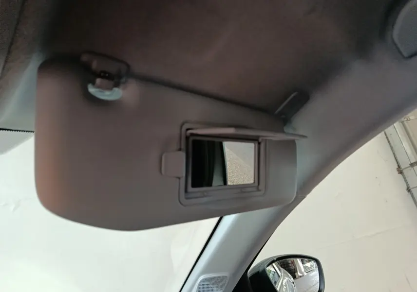 Détail du pare-soleil avec miroir de courtoisie ouvert dans l’habitacle gris clair d’une Peugeot 208 Hybrid 2025.