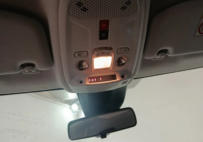 Vue intérieure du plafond avant de la Peugeot 208 Hybrid 100 e-DCS6 Style 2025 gris clair, avec plafonnier et rétroviseur central.