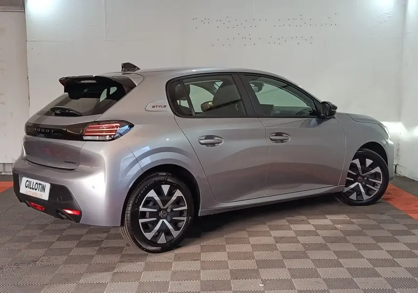 Peugeot 208 Hybrid gris clair vue 3/4 arrière droit, avec jantes stylisées et logo Style sur l'aile arrière.