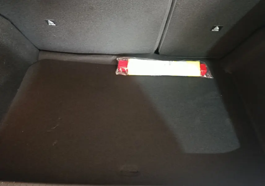 Coffre spacieux de Peugeot 208 Hybrid gris clair, vue intérieure montrant un triangle de signalisation rangé au fond.