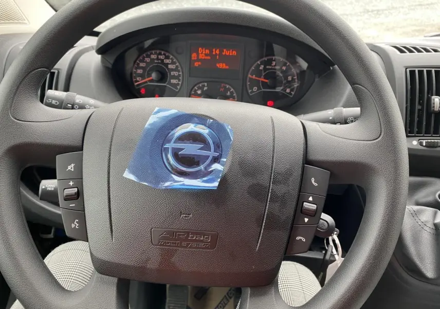 Vue rapprochée du volant d'un Opel Movano Fourgon 2022, avec commandes intégrées et tableau de bord numérique.