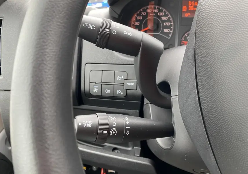 Gros plan sur la colonne de direction de l'Opel Movano Fourgon 2022, montrant les commandes du régulateur et des phares.