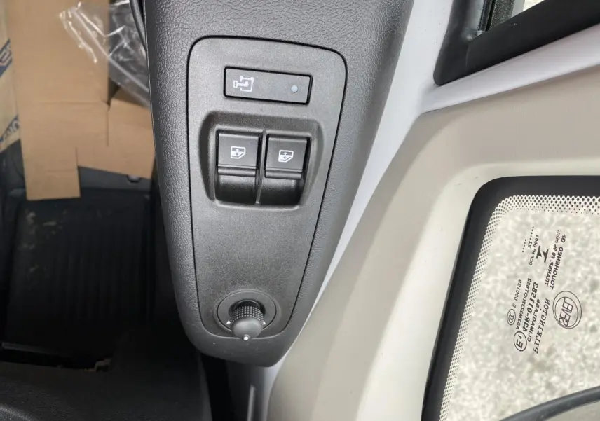 Détail des commandes de réglage des rétroviseurs et vitres côté conducteur dans un Opel Movano Fourgon blanc 2022.