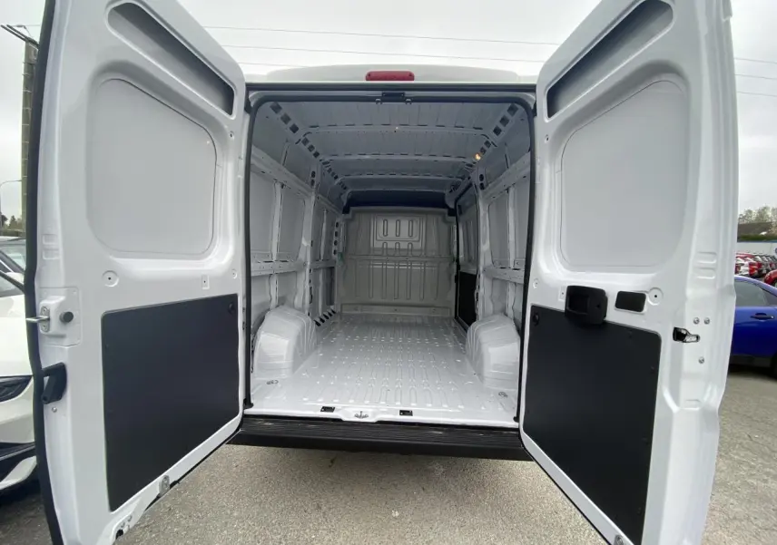 Vue arrière du fourgon blanc Opel Movano 2022 avec portes ouvertes dévoilant l'intérieur spacieux et tôlé.