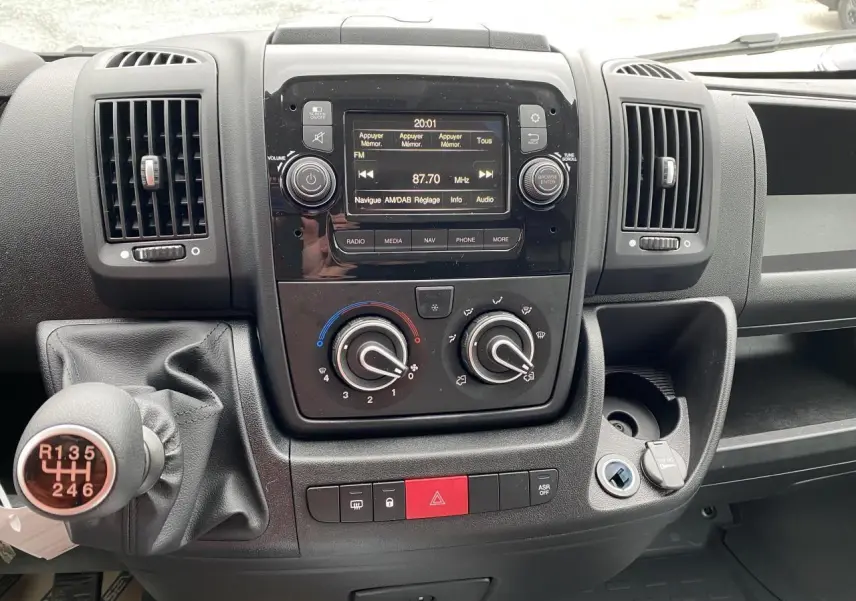 Vue rapprochée du tableau de bord noir de l'Opel Movano Fourgon 2022 avec commandes manuelles et écran multimédia.