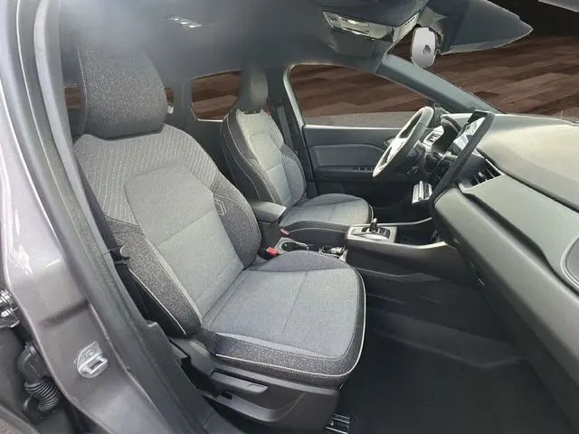 Vue intérieure côté gauche du Renault Captur 2025 gris Cassiopée, sièges tissu gris et tableau de bord moderne.