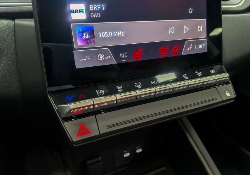 Gros plan sur la console centrale du Renault Captur 2025 montrant l'écran tactile et les commandes climatisation et sécurité.