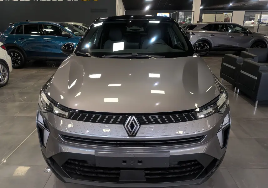 Vue frontale d'un Renault Captur 2025 gris Cassiopé avec toit noir, éclairage LED et calandre moderne en showroom.