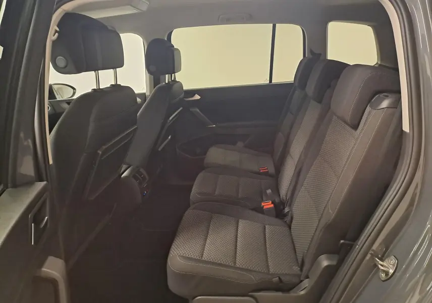 Vue intérieure côté droit du Volkswagen Touran 2024 gris Dauphin, montrant les sièges arrière en tissu noir et les appuie-têtes.