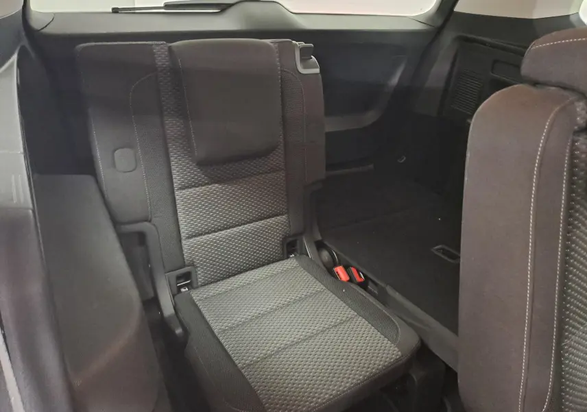 Vue intérieure du siège arrière droit relevé du Volkswagen Touran 2024, tissu gris foncé avec détails texturés.