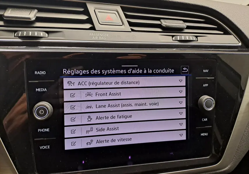 Écran tactile central du Volkswagen Touran 2024 affichant les réglages des aides à la conduite, vue de face en intérieur.