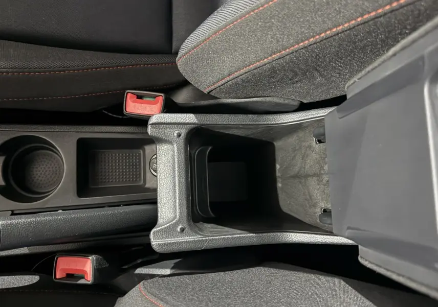 Vue plongeante sur la console centrale ouverte de la SEAT IBIZA 1.0 TSI 110 FR gris foncé, avec sièges tissu gris et coutures rouges.