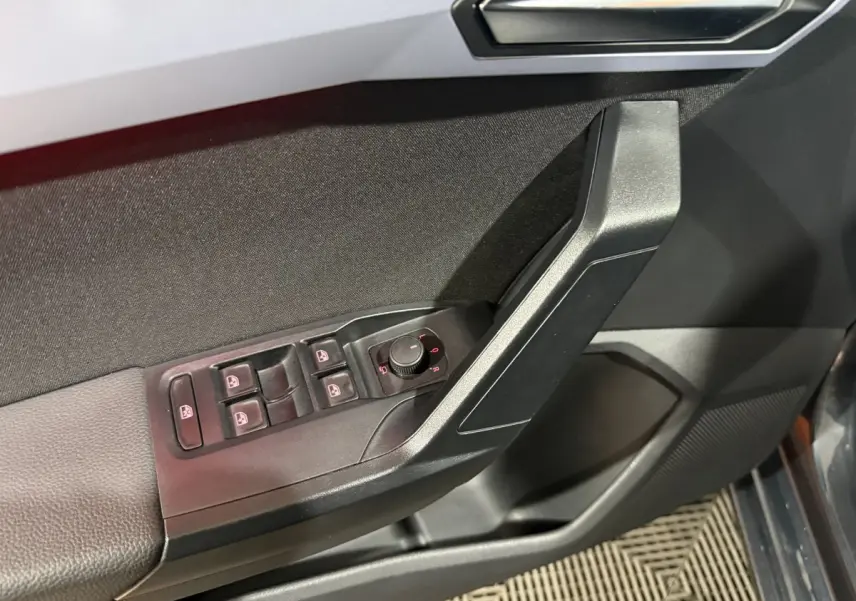 Gros plan sur la porte côté conducteur de la SEAT Ibiza gris foncé, montrant les commandes électriques des vitres et des rétroviseurs.