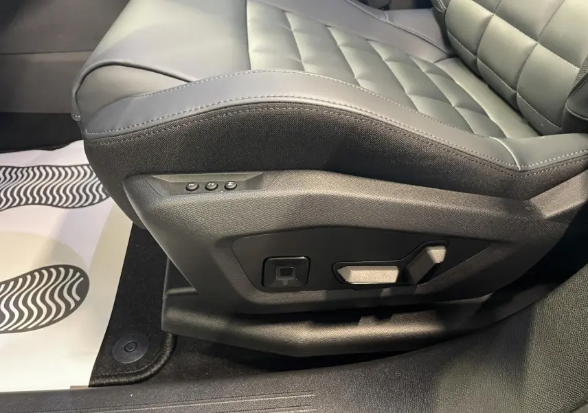 Gros plan sur le siège conducteur gris du Citroën C5 Aircross 1.2i Hybride avec commandes électriques latérales.