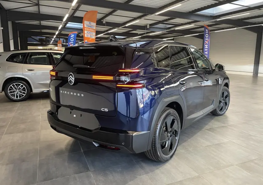 Vue 3/4 arrière droite du Citroën C5 Aircross bleu Azul avec feux arrière LED allumés en showroom.
