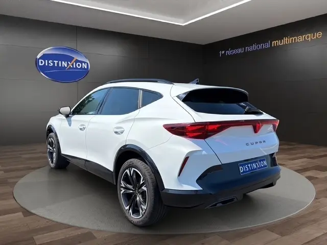 Vue 3/4 arrière droite d'un CUPRA Formentor blanc 2025 avec jantes noires et toit noir dans un showroom.