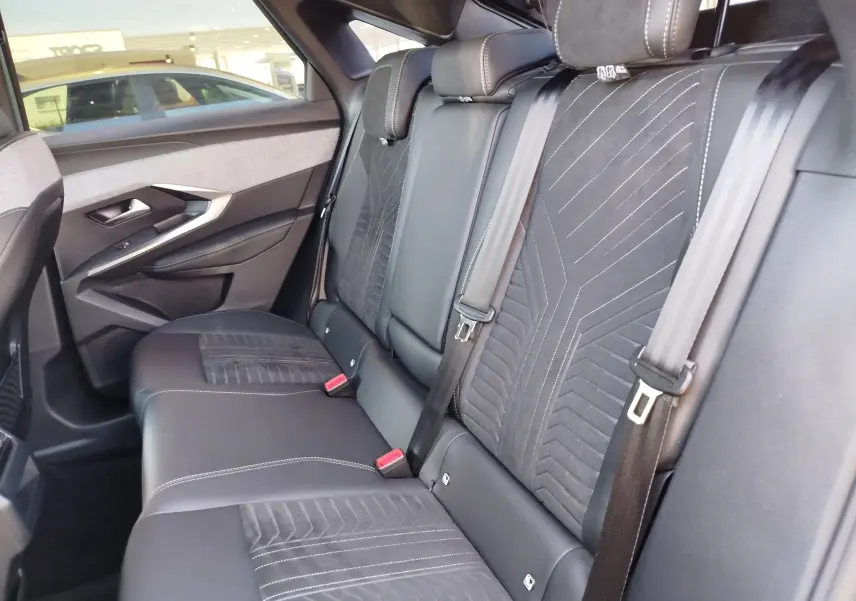 Vue intérieure arrière côté gauche du Peugeot 3008 2024, sièges en cuir noir avec surpiqûres blanches et détails en tissu.