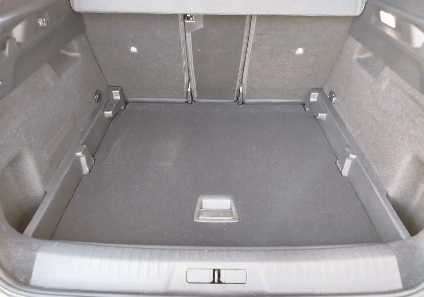 Coffre spacieux du Peugeot 3008 2024 vu de l'intérieur, revêtement noir et banquette arrière rabattue.