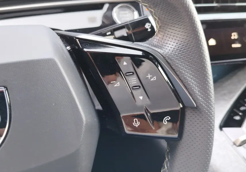 Gros plan sur les commandes vocales et téléphone au volant perforé d’un Peugeot 3008 Bleu Obsession 2024.