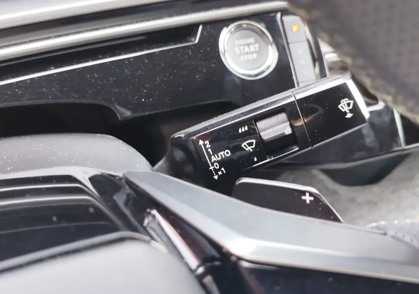 Gros plan sur la commande d’essuie-glace noire et le bouton start/stop du tableau de bord intérieur du Peugeot 3008 2024.