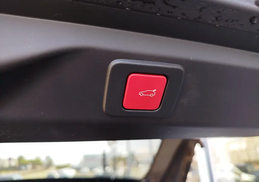 Gros plan sur le bouton rouge d'ouverture électrique du coffre du Peugeot 3008 Bleu Obsession, vue intérieure arrière.