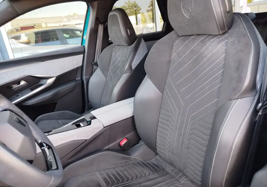 Vue intérieure côté conducteur du Peugeot 3008 2024 bleu Obsession, sièges sport en cuir et alcantara avec surpiqûres blanches.