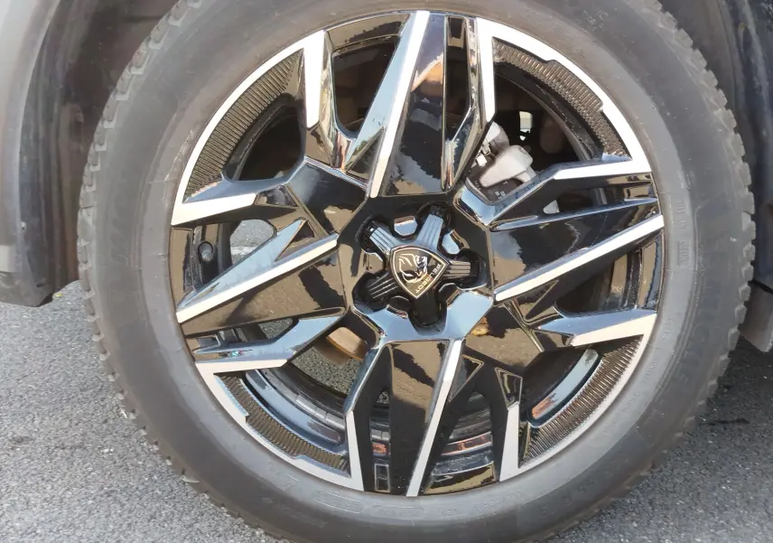 Gros plan sur la jante noire et argentée du Peugeot 3008 1.2 Hybride 136 ch GT, avec logo Lion central visible.