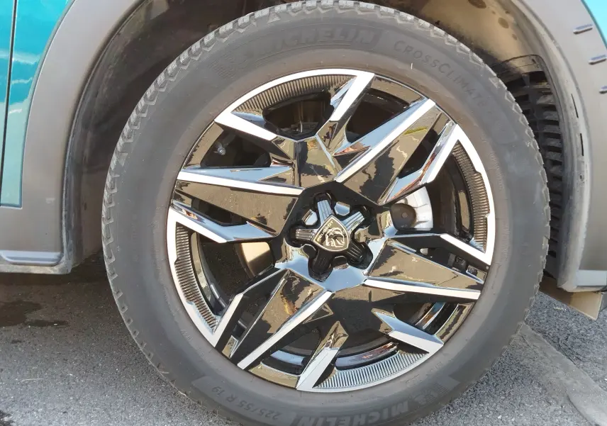 Gros plan sur la roue avant gauche du Peugeot 3008 2024 Bleu Obsession avec jante alliage noire et chromée distinctive.