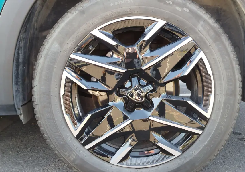 Gros plan sur la jante noire et chromée du Peugeot 3008 Bleu Obsession, mettant en valeur le logo central et le pneu Michelin.