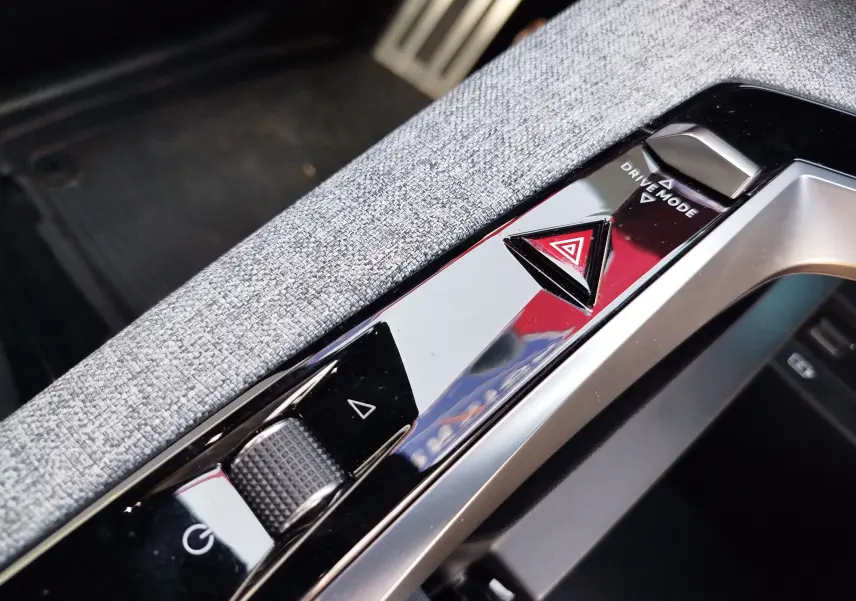 Gros plan sur la console centrale du Peugeot 3008 2024, avec bouton d’alerte triangulaire rouge et molette de réglage.