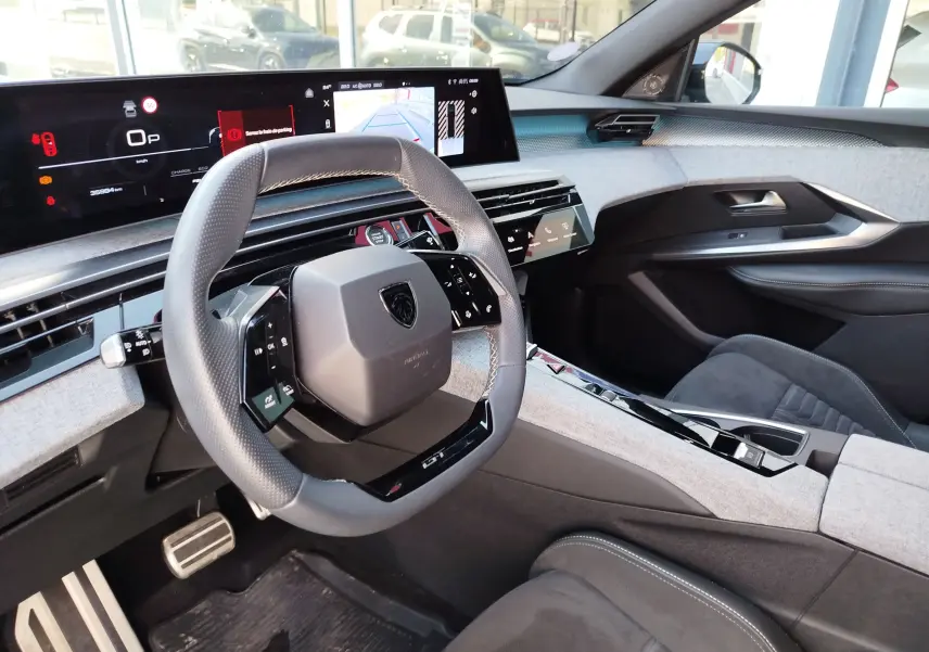 Intérieur du Peugeot 3008 Hybride 2024, vue du poste de conduite avec volant compact et écran numérique large.