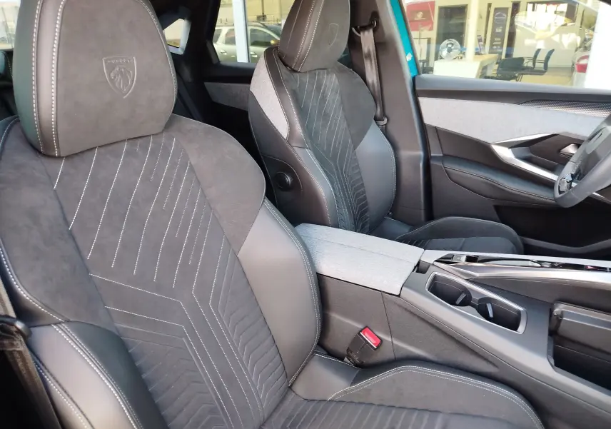 Vue intérieure côté avant droit du Peugeot 3008 2024, sièges en cuir et alcantara gris foncé avec surpiqûres blanches.