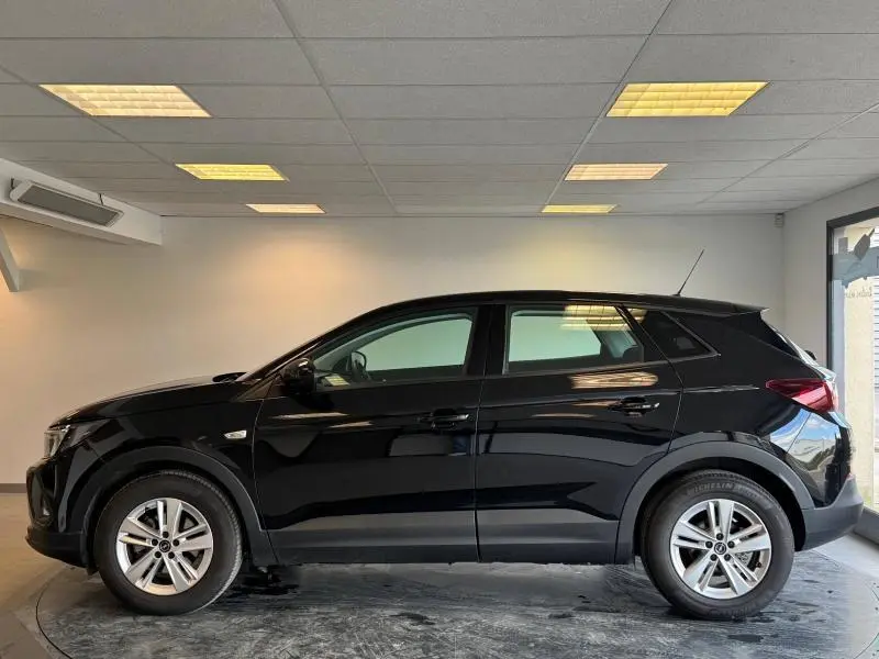 Profil côté gauche d'un Opel Grandland 1.2 Turbo 130ch Design&Tech noir Karbon métallisé en intérieur showroom.