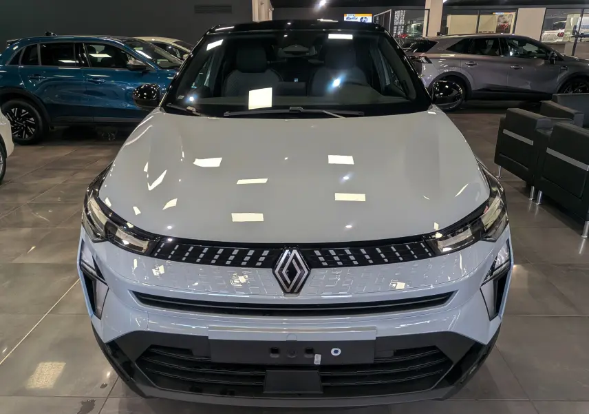 Vue avant d'un Renault Captur 2025 gris Rafale avec toit noir, éclairage LED et calandre moderne en showroom.