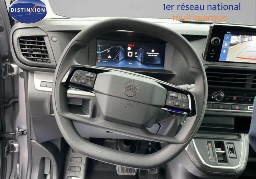 Vue intérieure centrée sur le volant et le tableau de bord du Citroën Jumpy gris Artense, avec écran multimédia et caméra de recul.