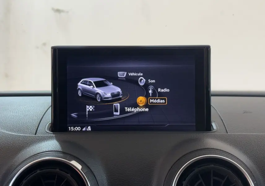 Écran multimédia central affichant le menu principal avec une Audi A3 grise en vue 3/4 avant.