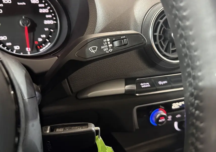 Détail intérieur côté gauche d'un Audi A3 bleu 2018, montrant commandes essuie-glace, ventilation et volant cuir.