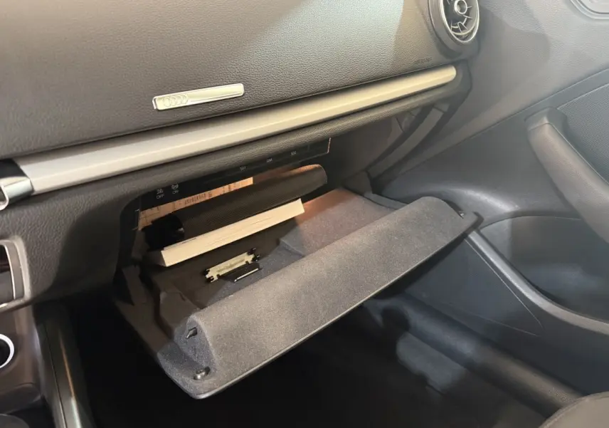 Vue intérieure côté passager de la boîte à gants ouverte de l'Audi A3 Business Line 2018 avec tableau de bord noir.