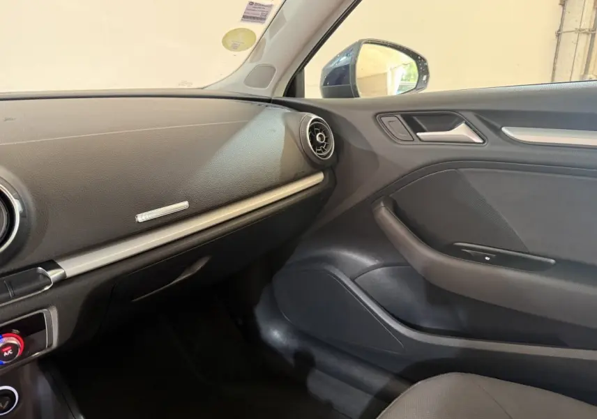 Vue intérieure côté passager de l’Audi A3 2.0 TDI 150 Business Line 2018, tableau de bord et porte en noir.