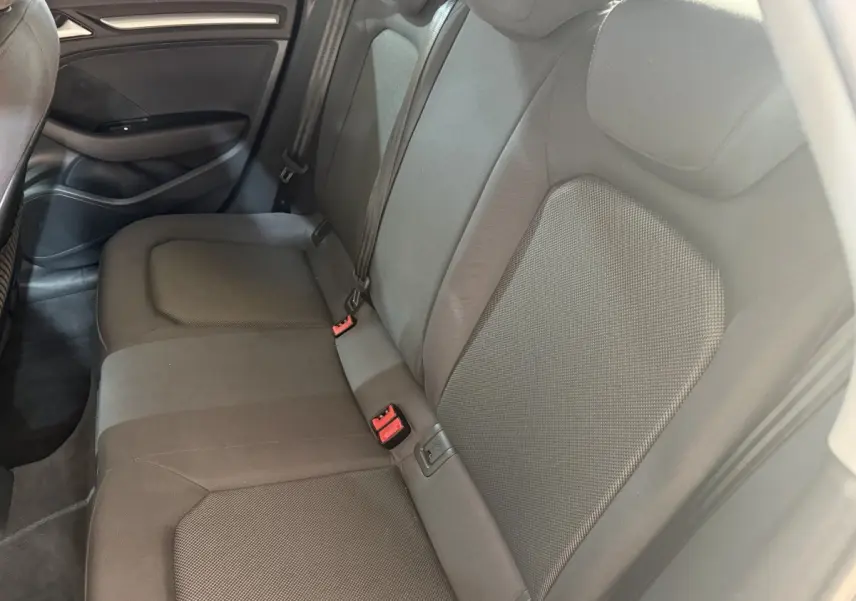 Vue intérieure des sièges arrière gris foncé de l'Audi A3 2018, avec ceintures et habillage de porte visible.