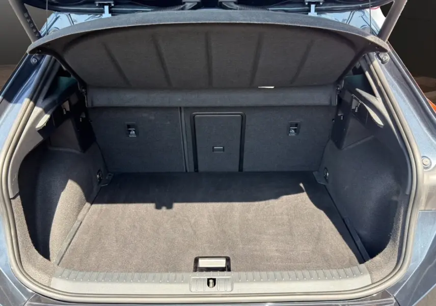 Coffre ouvert vu de l'arrière d'une CUPRA Formentor gris foncé, montrant un espace de chargement propre et spacieux.