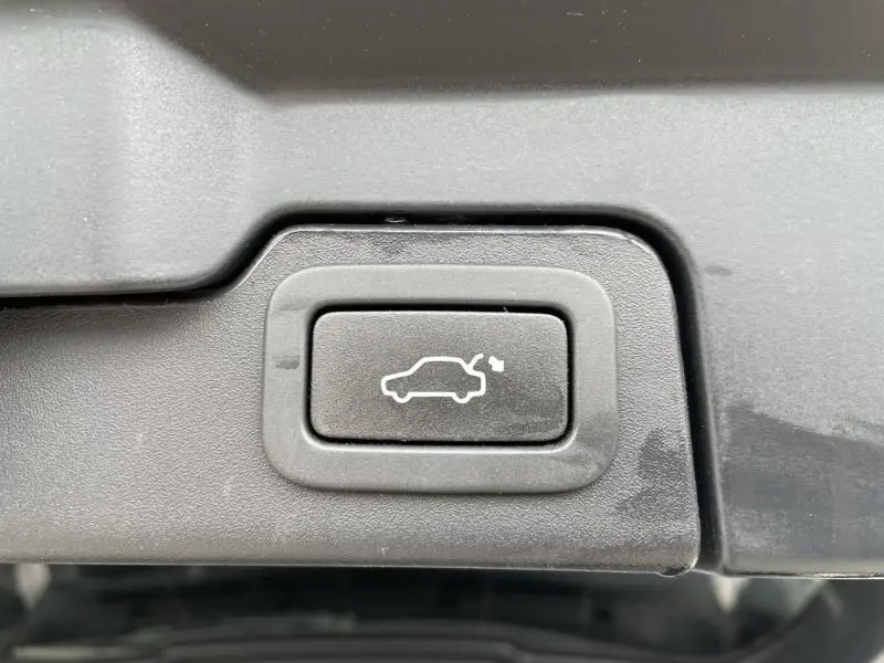 Bouton d'ouverture du coffre arrière sur un Range Rover Evoque marron métal, vue rapprochée du hayon arrière.