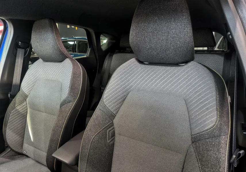 Gros plan sur les sièges avant en tissu gris du Renault Captur 2025, intérieur moderne et épuré.