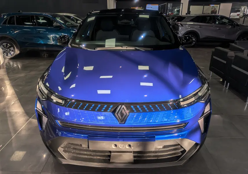 Vue frontale du Renault Captur 2025 bleu Iron avec toit noir, mettant en valeur sa calandre lumineuse et son design moderne.